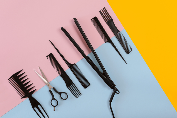 Various hair styling devices on the color blue, yellow, pink paper background, top view
