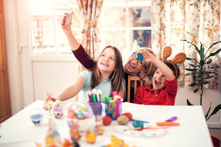 Happy mother with children painting Easter eggs at home Happy mother with children painting Easter eggs at home