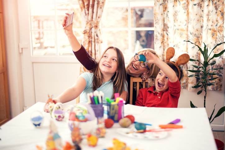 Happy mother with children painting Easter eggs at home