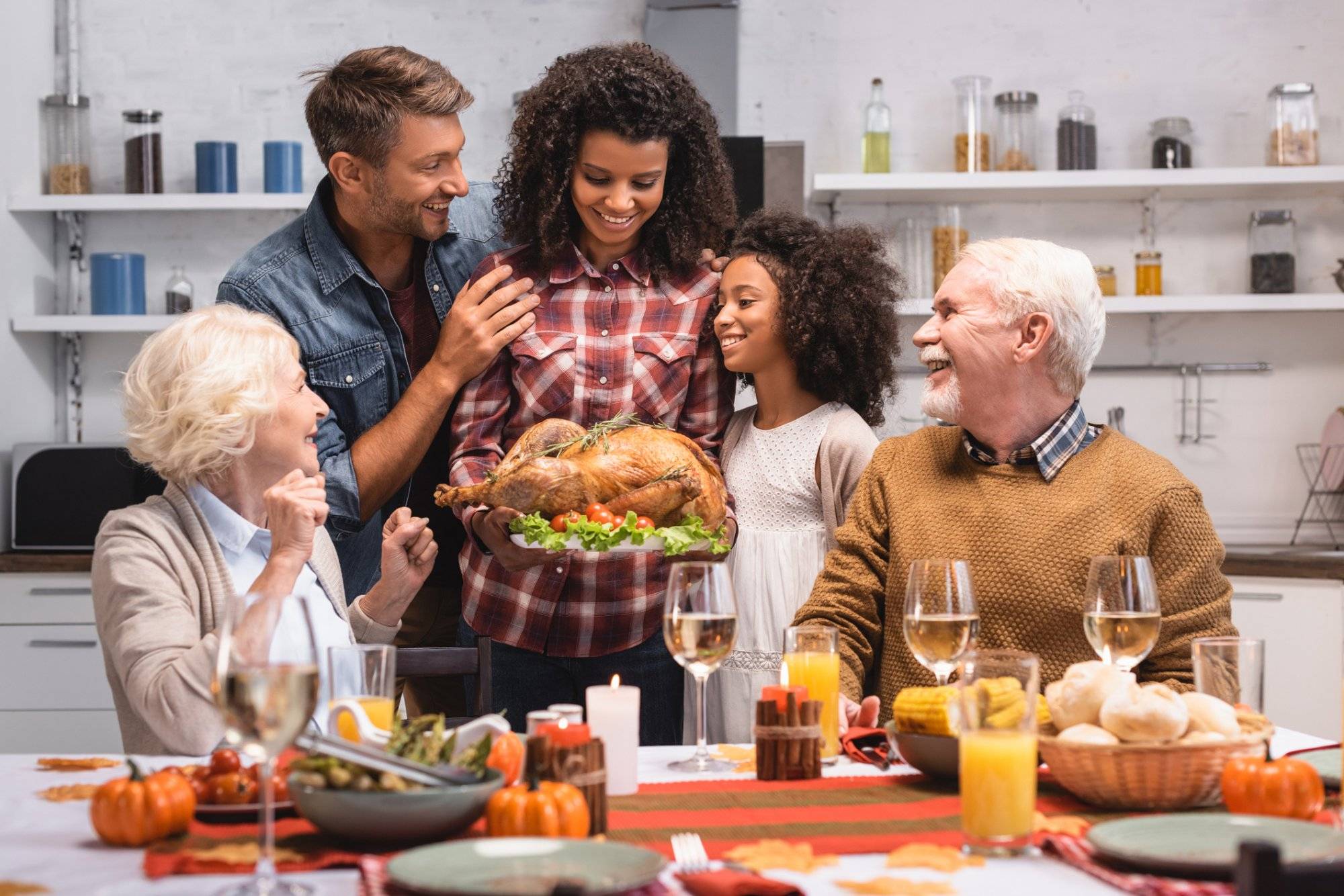 Selective focus of african american woman holding turkey near family during thanksgiving celebration Selective focus of african american woman holding turkey near family during thanksgiving celebration