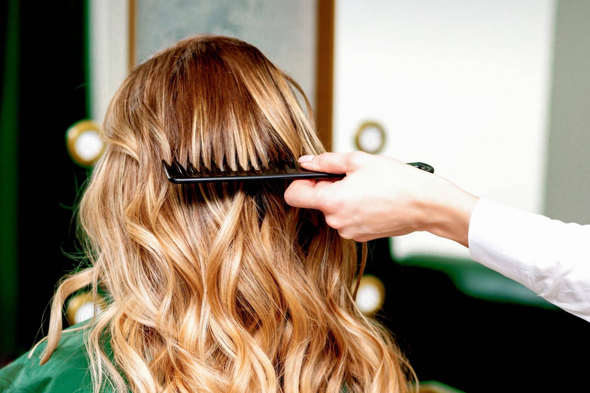 Hairdresser combing wavy hair of woman Hairdresser combing wavy hair of woman