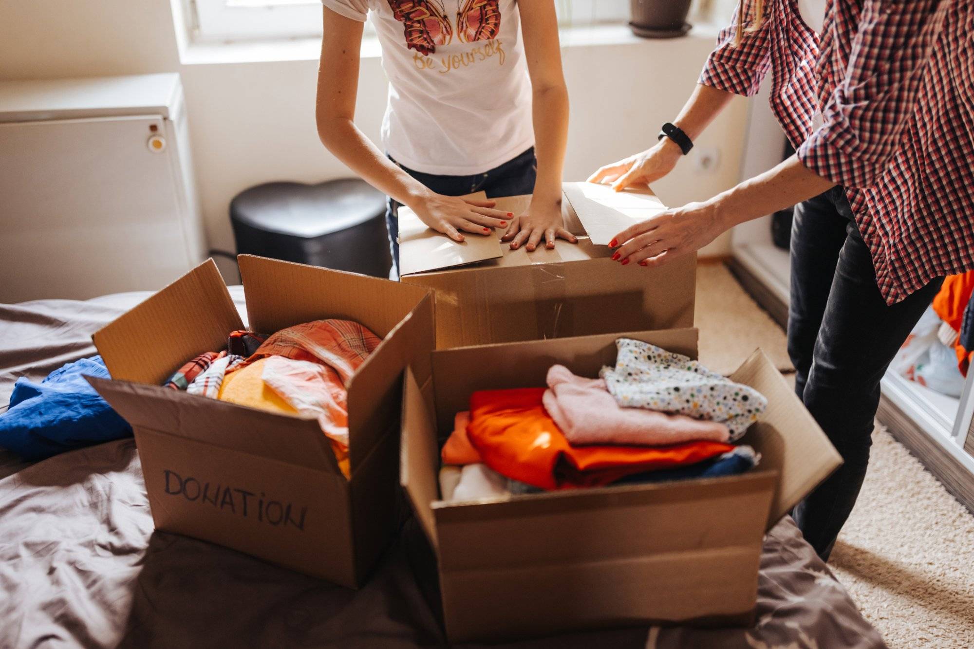 Mother and daughter filling a boxes with clothes for donations