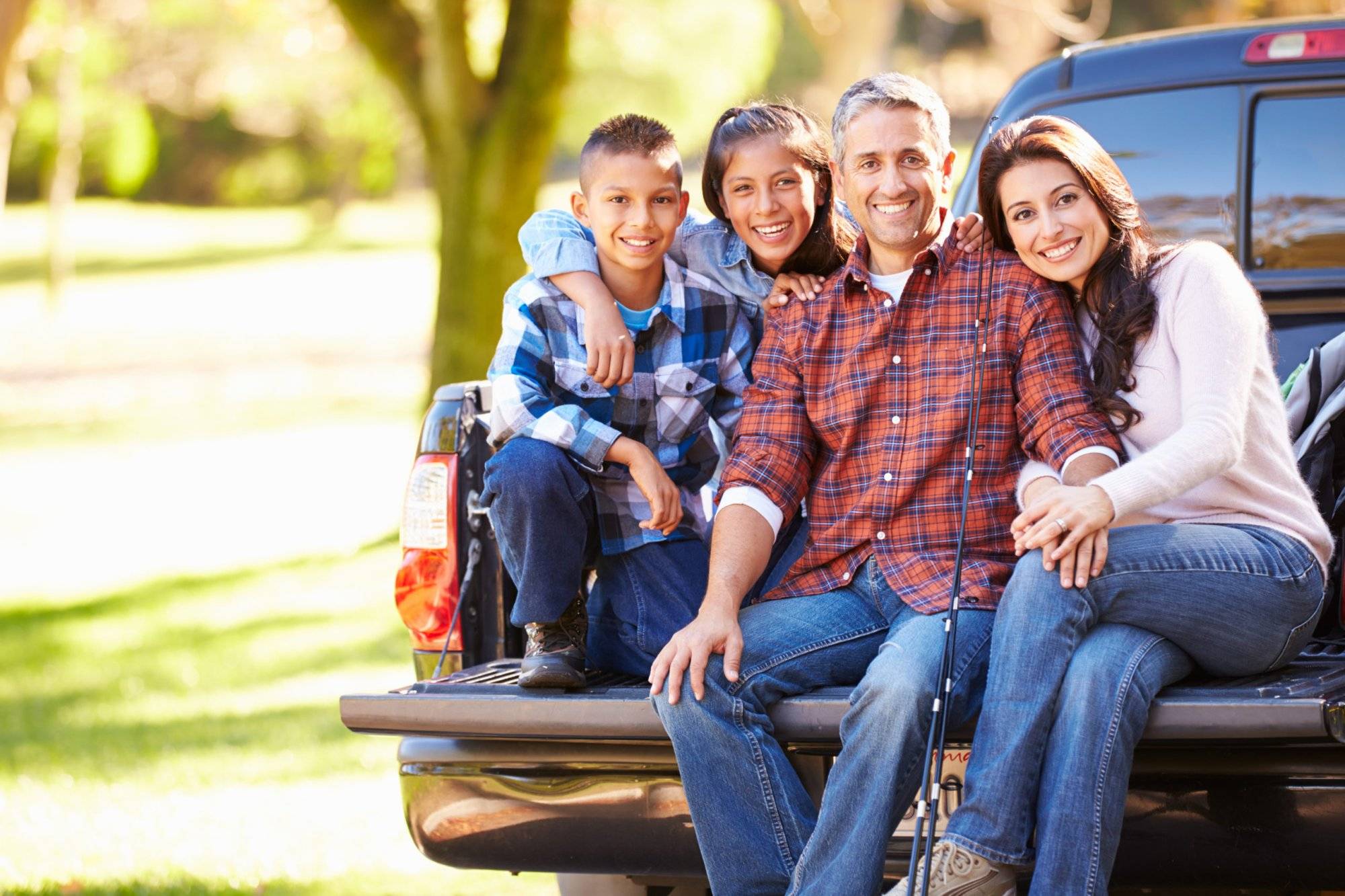 Family Sitting In Pick Up Truck On Camping Holiday Family Sitting In Pick Up Truck On Camping Holiday