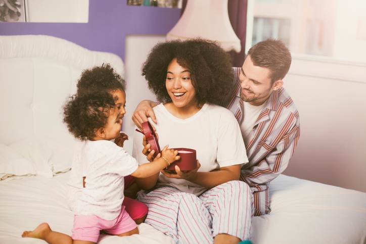 Family bringing mother presents in bed