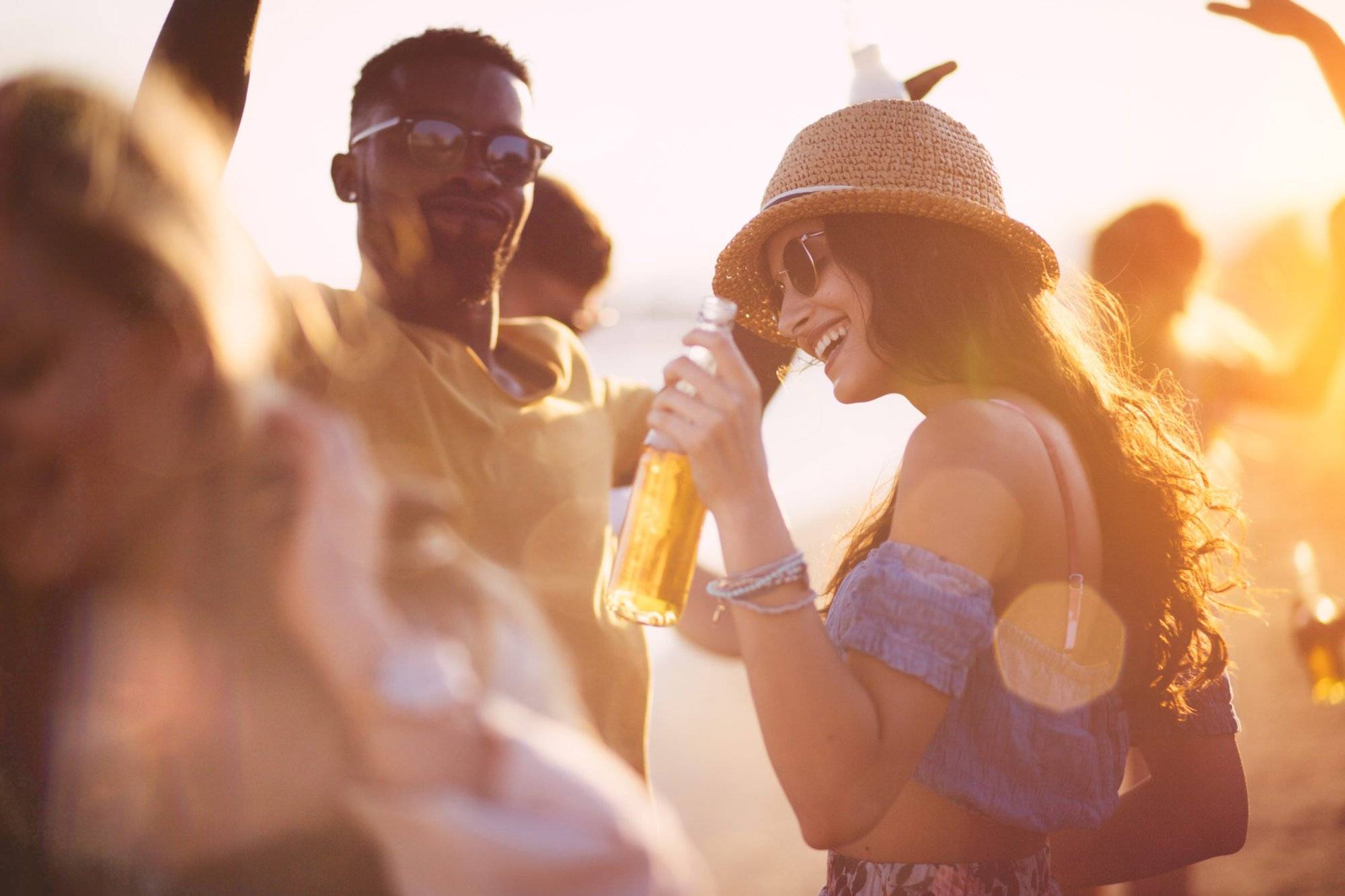 Young multi-ethnic hipster friends dancing at summer beach party